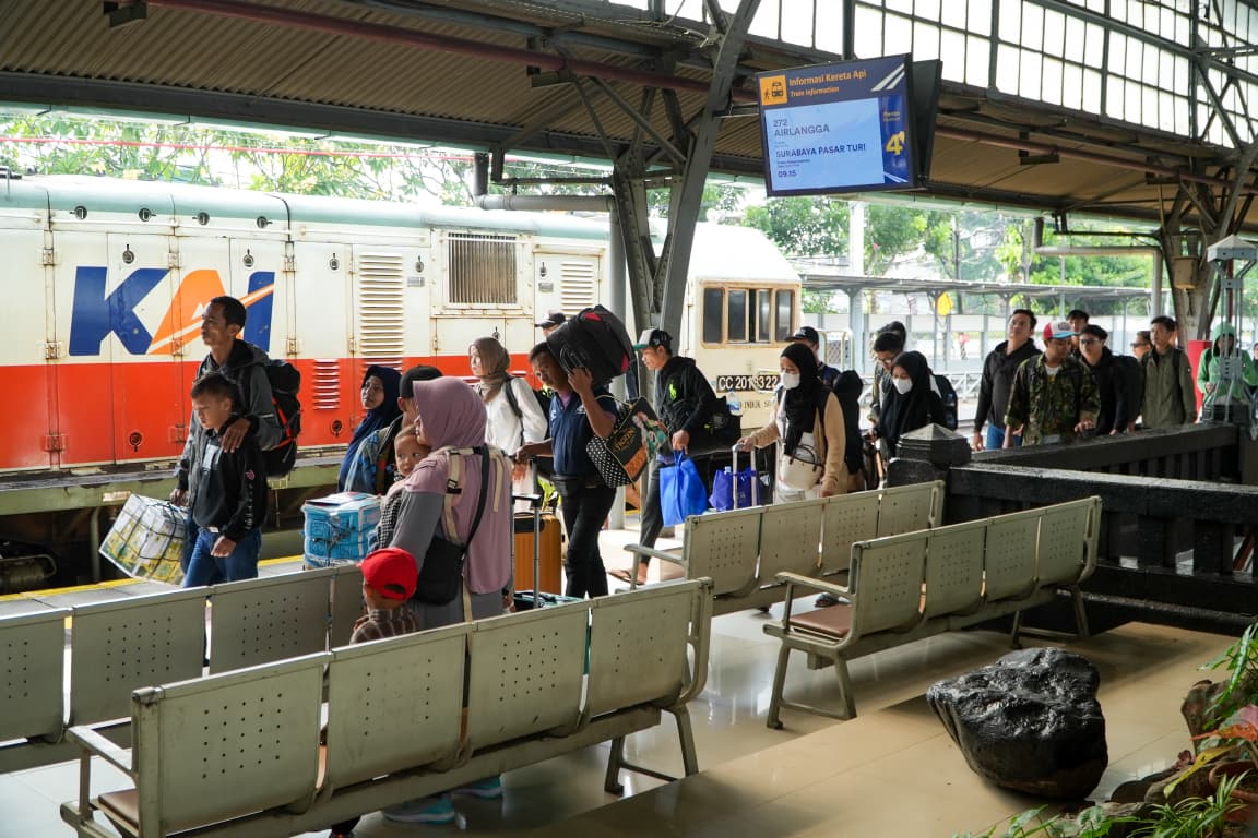 Tampak para pelanggan kereta api jarak jauh berjalan menuju rangkaian kereta 