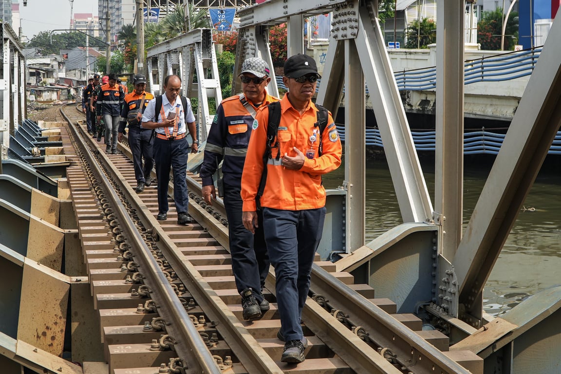 Pekerja KAI Daop 1 Jakarta saat berjalan menyusuri rel di jembatan untuk memastikan jalur KA tidak tergenang akibat adanya sampah dibawah jalur KA.