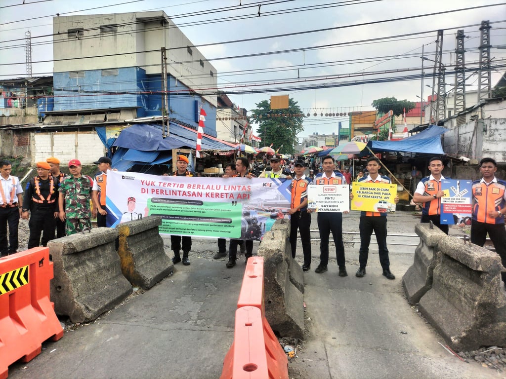 Para pekerja PT KAI Daop 1 Jakarta dan KAI Commuter bentangkan spanduk imbauan tertib lalu lintas di JPL 01 Bogor
