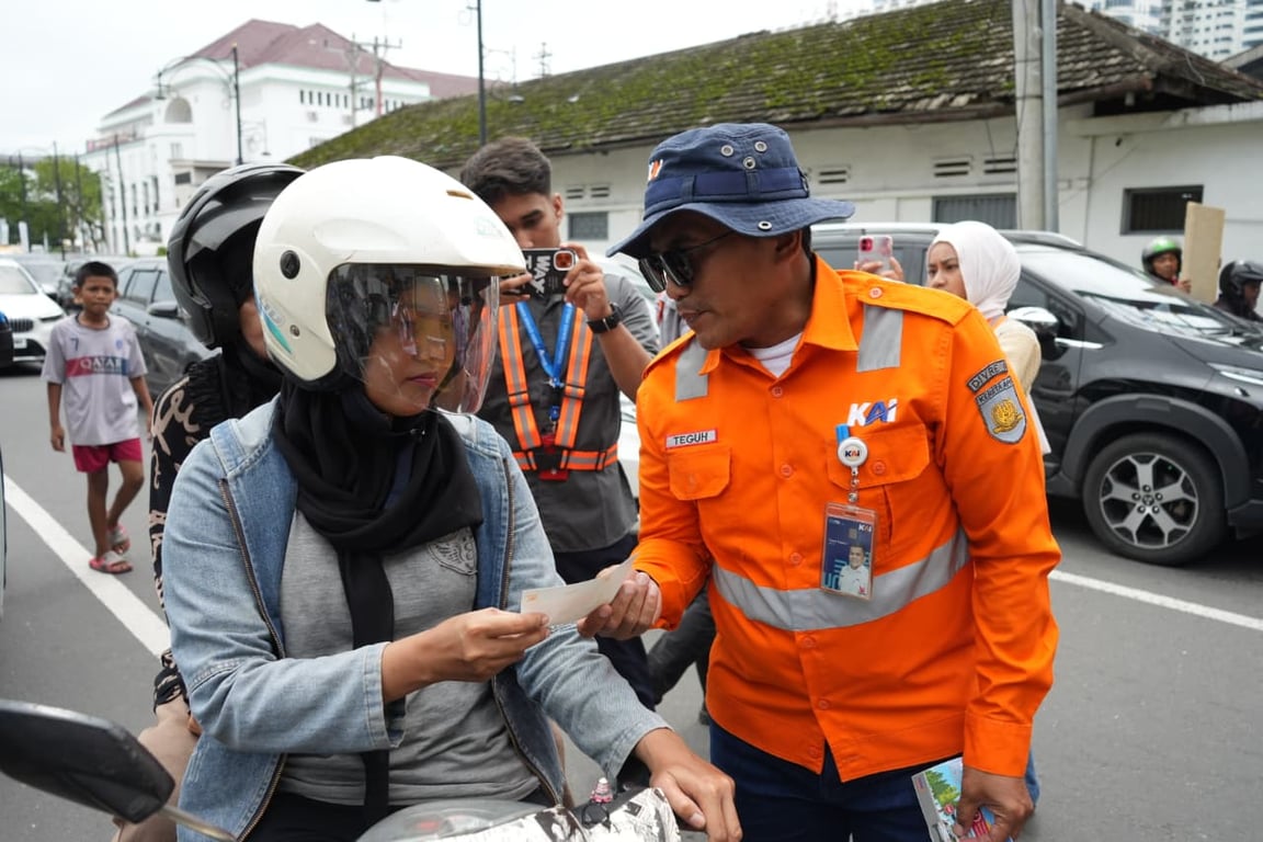 Deputy Vice President KAI Divre I Sumut, Teguh Triyono (kanan) memberikan stiker edukasi tertib di perlintasan sebidang di Jl. HM Yamin Kota Medan, Minggu (12/10/2025).