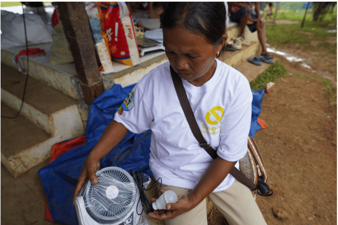 Jovita, a 53-year-old resident in Barangay New Aklan in Glan, Sarangani province, unboxes the solar lamp with built-in fan at their evacuation site on June 16, 2026.