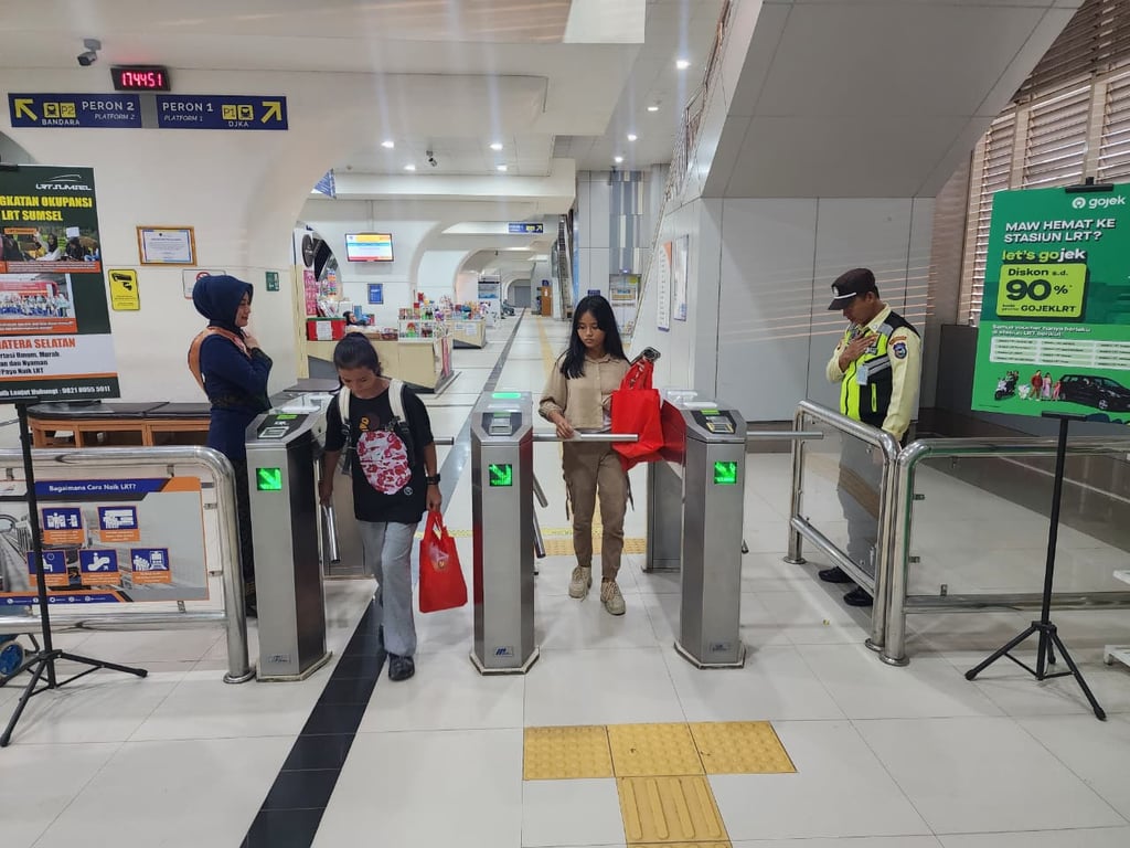 Foto : Penumpang LRT saat tap out di gate stasiun LRT