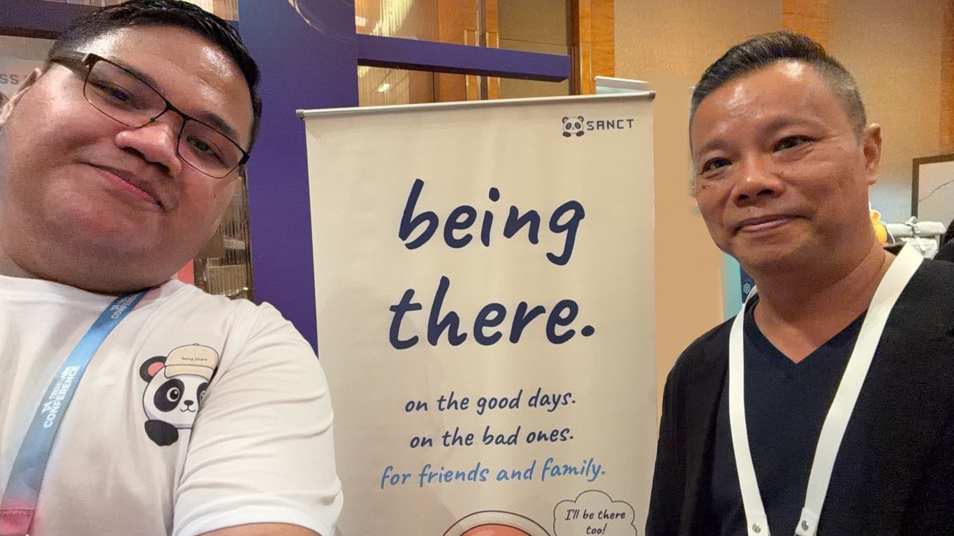 Seorang pengunjung bersama Sion Abednego di depan banner booth.