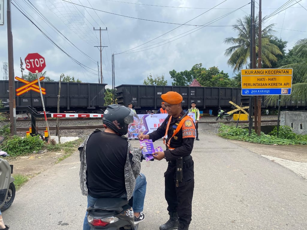 Foto : Polisi Khusus Kereta Api (Polsuska) saat melakukan sosialisasi keselamatan di perlintasan sebidang dengan membagikan stiker himbauan untuk disiplin di perlintasan sebidang