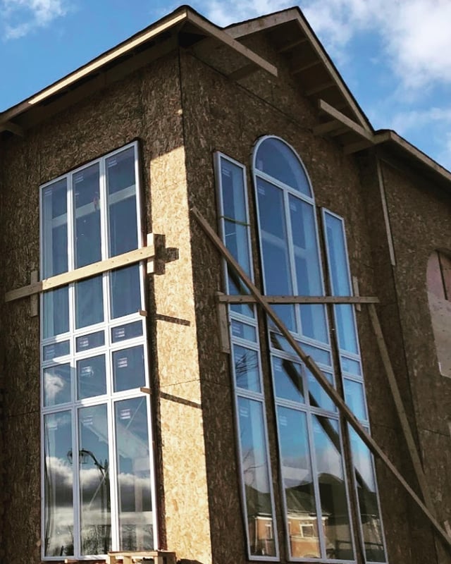 Client-installed white Panes windows with tall rectangular and arched sections in a Brampton home under construction