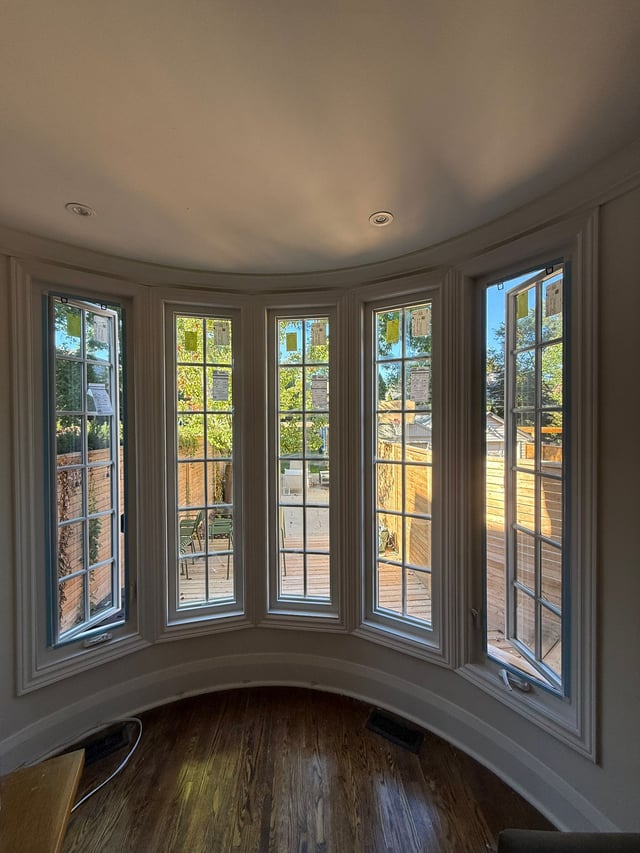 Curved row of tall white-framed windows with rectangular grids and a continuous interior ledge