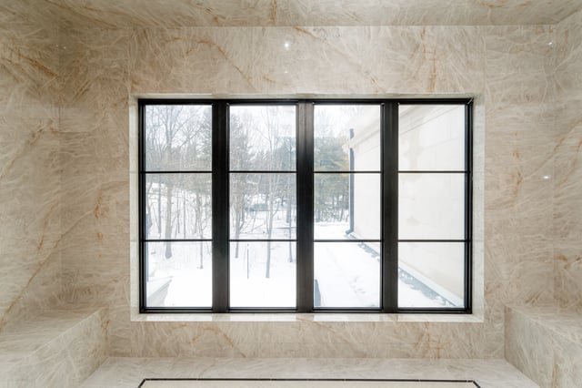 Dark-framed window with a rectangular grid pattern in a light stone interior