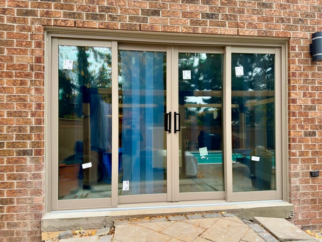 Tan four-panel sliding patio door in a brick wall above stone steps
