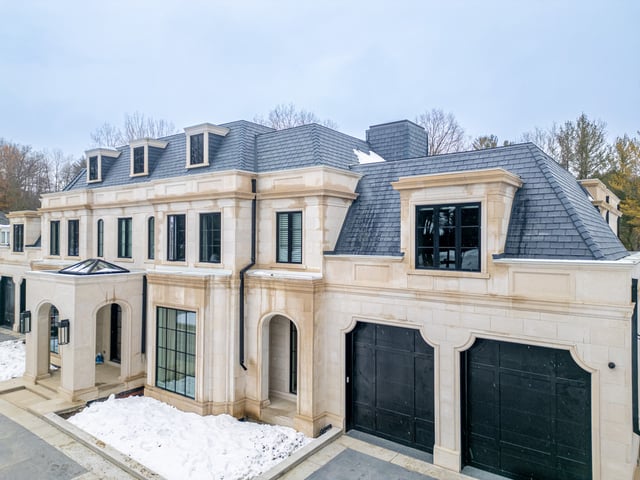 Stone home with dark-framed windows across the front elevation and dormers