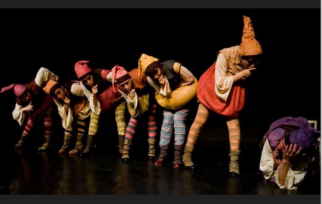 6 גמדים עומדים בשורה מסתכלים על גמד נוסף מכופף על הרצפה ועושים לו שוש