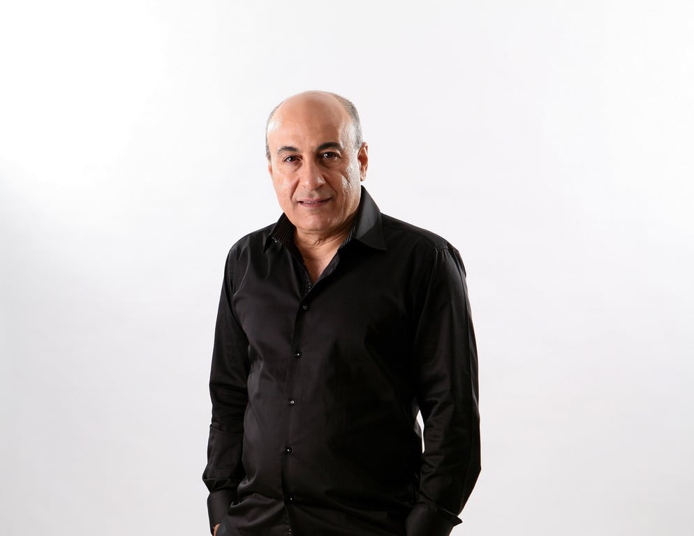 איציק קלה עם חולצה מכופתרת עומד ומחייך