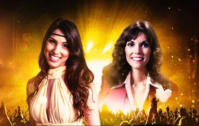 שתי בנות מחייכות למצלמה ומתחתן ברקע קהל מרים ידיים