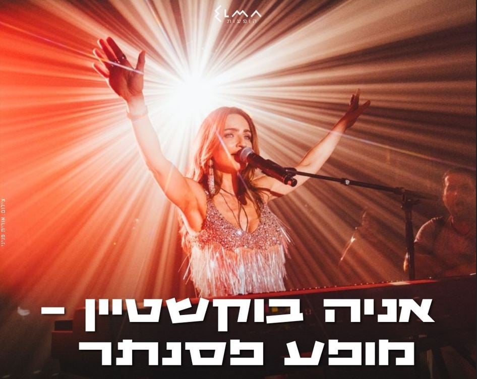 אניה בוקשטיין שרה למיקרופון על הבמה ומרימה ידיים