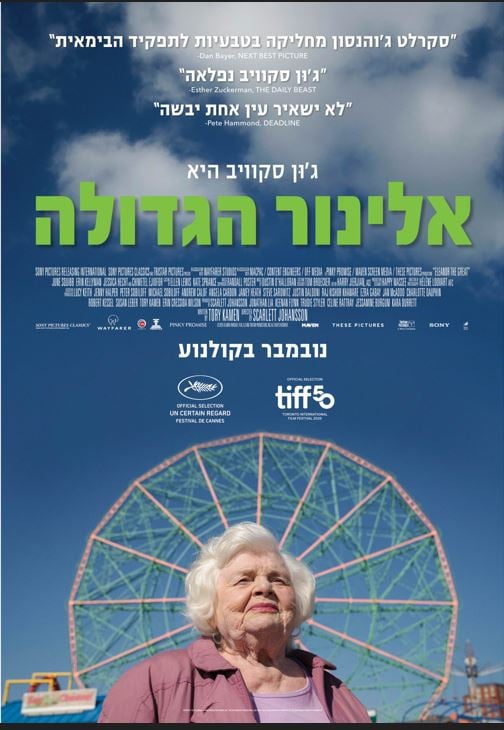 אישה מבוגרת מסתכלת לאופק ומאחוריה גלגל ענק