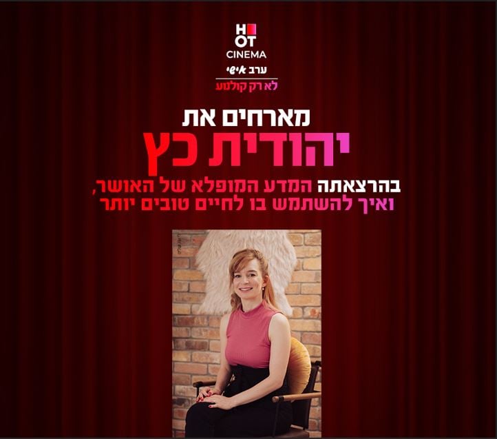 צילום של יהודית כץ יושבת על כיסא ומחייכת