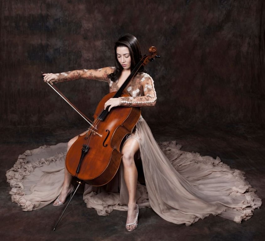 בחורה יושבת בשמלה גדולה באמצע החדר מנגנת צ'לו