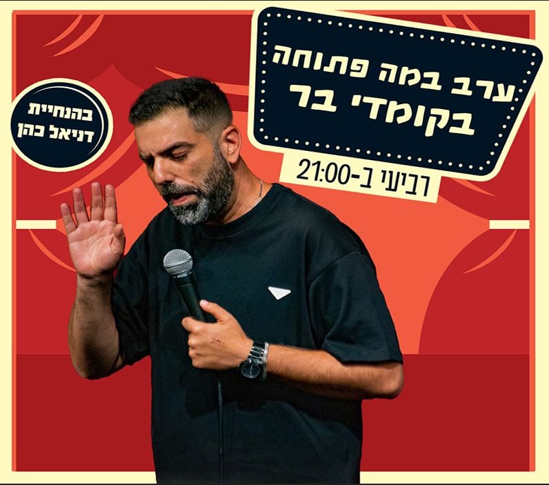 תמונה של דניאל כהן אוחז במיקרופון ומרים את ידו