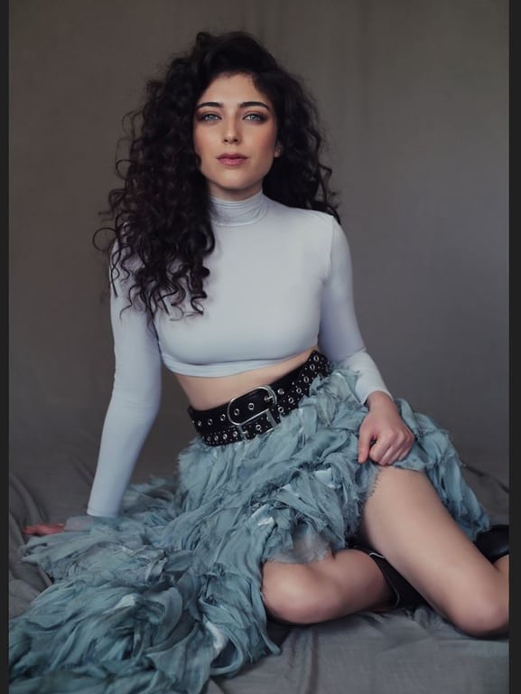 רוני דלומי יושבת על הרצפה נשענת על ידה