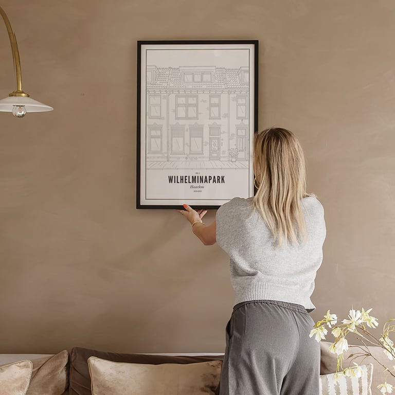 Une personne accroche l'illustration au mur 