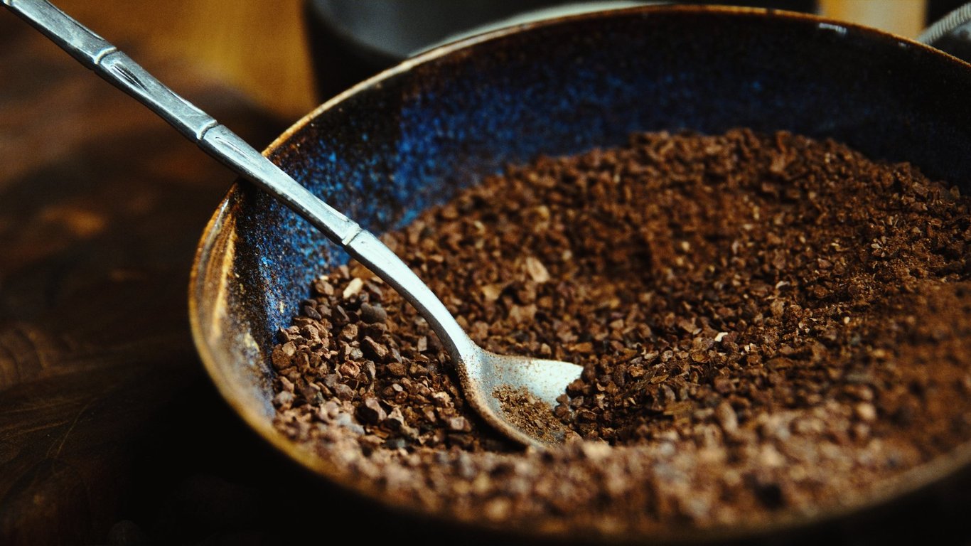 A bowl of roasted cacao beside a cup of brewed cacao