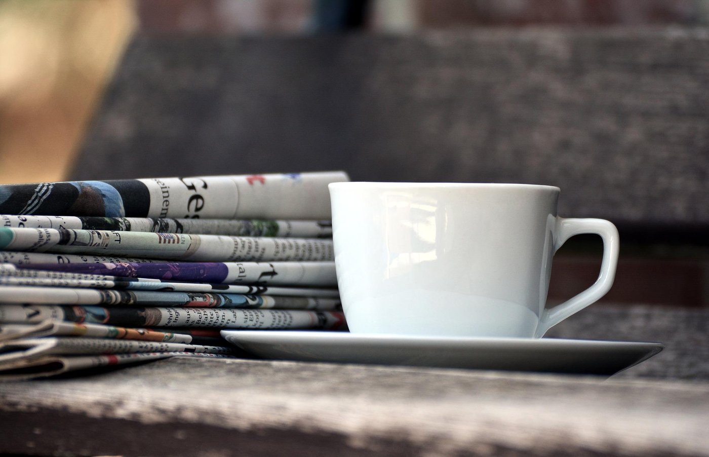 Eine Kaffeetasse vor einem Zeitungsstapel