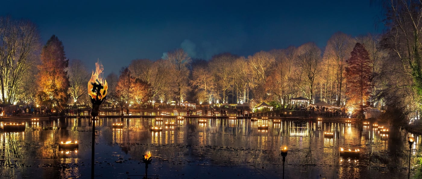see mit beleuchteten bäumen und feuer auf einem der außergewöhnlichen weihnachtsmärkte
