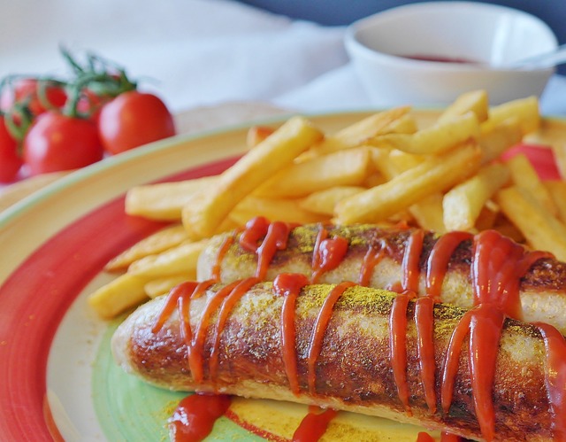 Ein Teller mit Currywurst und Pommes in einer der bekannten Imbissbuden