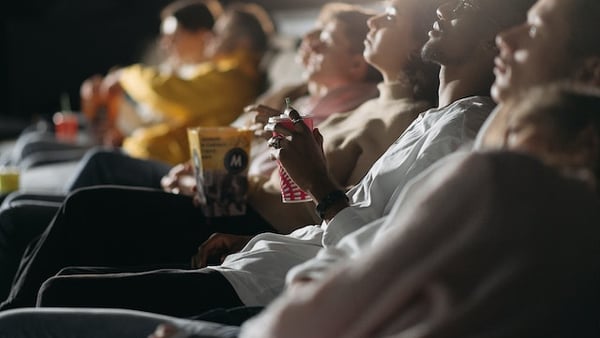 Kinobesucher:innen sitzen nebeneinander und betrachten die Leinwand
