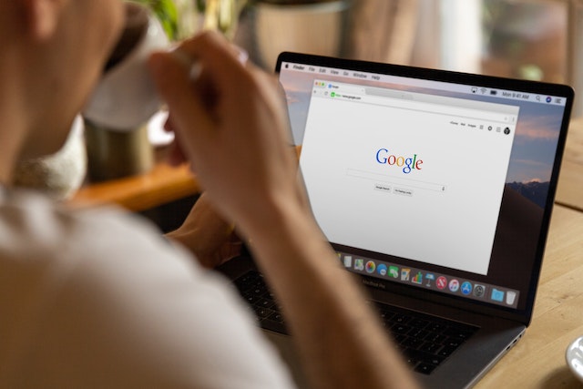Ein Mann sitzt vor seinem Laptop und hat die Google-Seite geöffnet