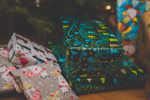 Verschiedene bunt verpackte Weihnachtsgeschenke liegen unter einem Weihnachtsbaum