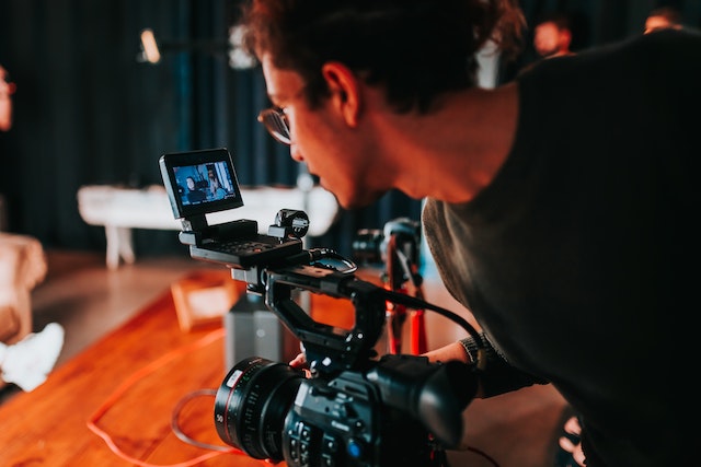 Ein Mann steht an einem Filmset hinter einer Kamera