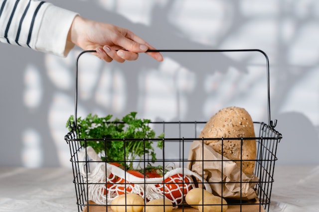 Ein Einkaufskorb mit Tomaten, Kartoffeln und Brot