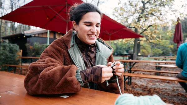 frau ist am häkeln in einem biergarten