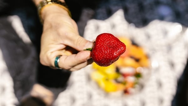 Eine Frauenhand hält eine Erdbeere.
