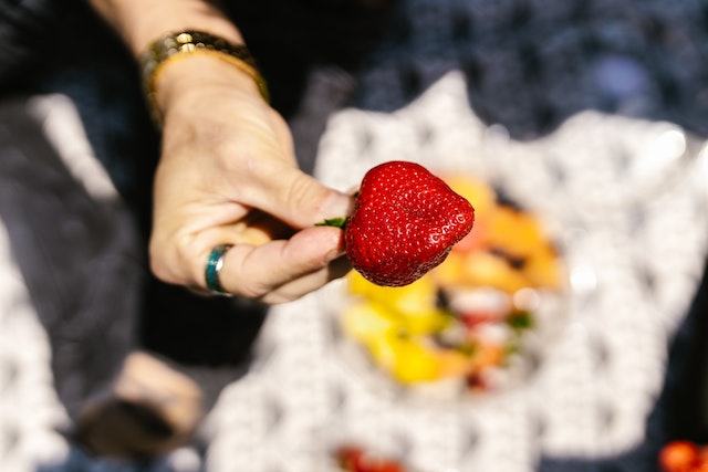 Eine Frauenhand hält eine Erdbeere.
