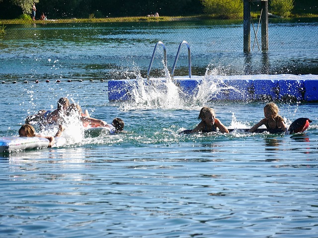 Mehrere Menschen springen in einen Badesee.