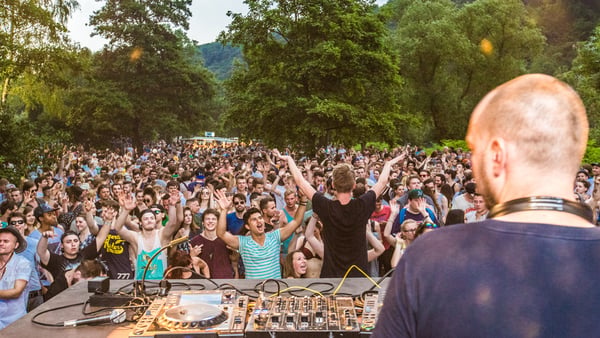 Ein DJ legt vor feiernden Menschen Musik auf