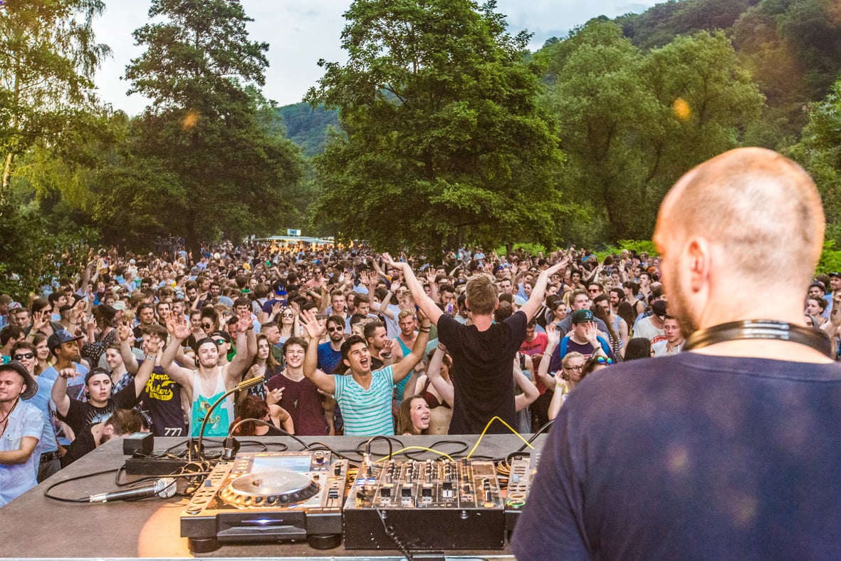 Ein DJ legt vor feiernden Menschen Musik auf