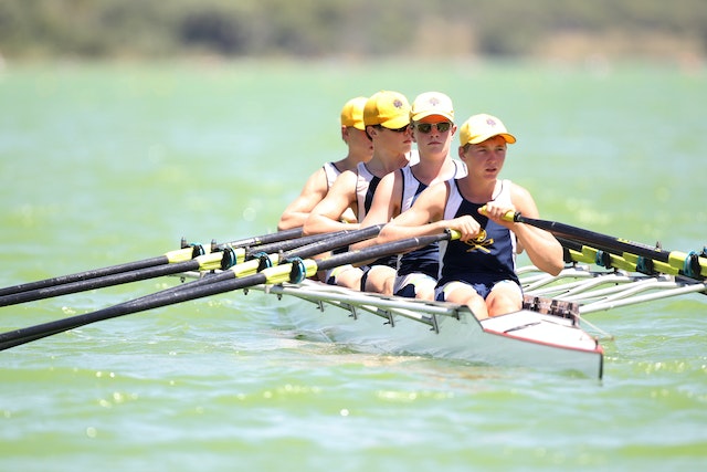 Vier Ruderer von einem Sportverein sitzen in einem Ruderboot.