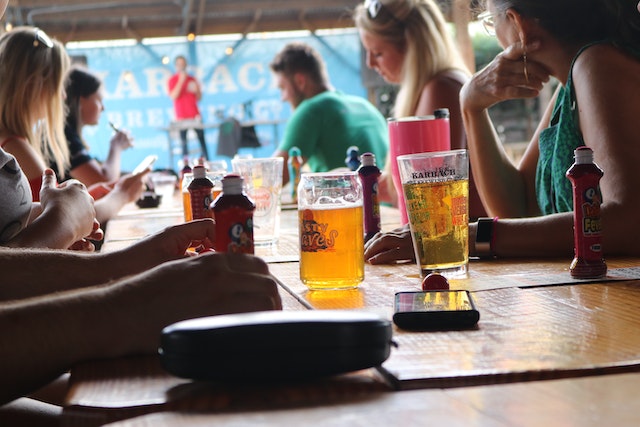 Menschen sitzen mit Getränken am Tisch einer Kneipe für ein Quiz
