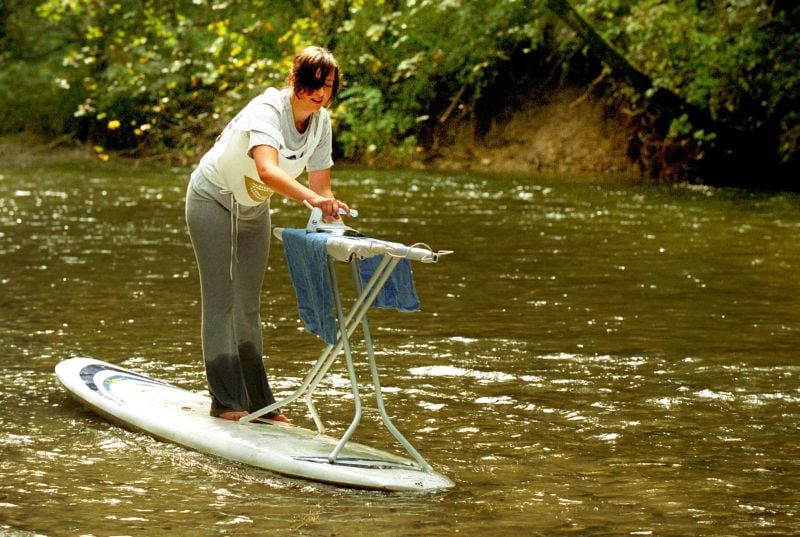 Eine Frau Bügelt auf einem Surfbrett. 