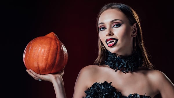 frau im halloween kostüm mit kürbis in der hand