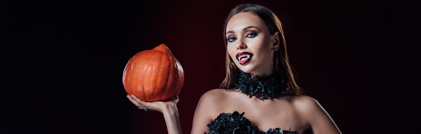 frau im halloween kostüm mit kürbis in der hand