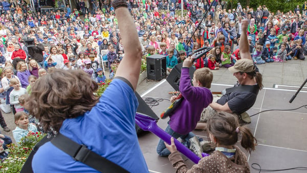 Kinder singen und tanzen mit einer Band auf der Bühne