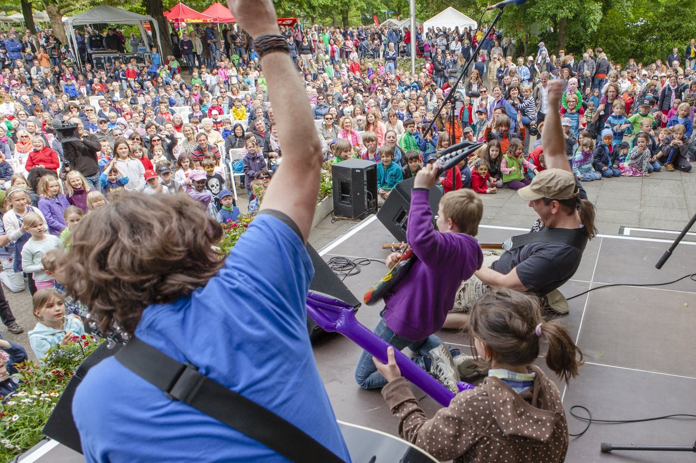 Kinder singen und tanzen mit einer Band auf der Bühne