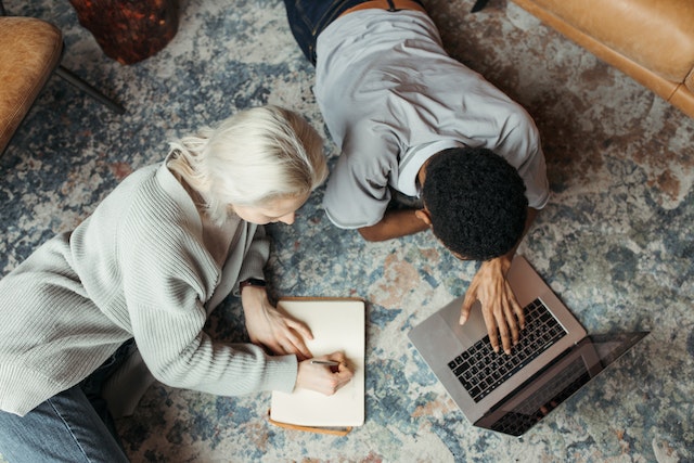 Schreibende Frau und Mann mit Buch und Laptop