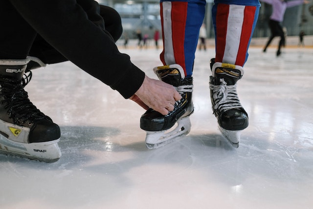 Schlittschuhe werden auf dem Eis geschnürt