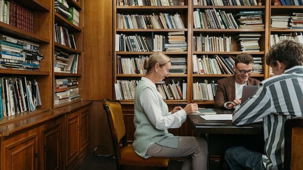 Zwei Menschen arbeiten in einer Bibliothek am Laptop