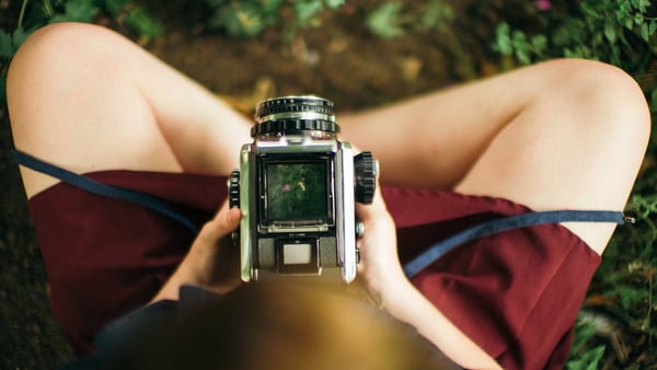 Blick von oben auf eine analoge Kamera im Schoß einer Person