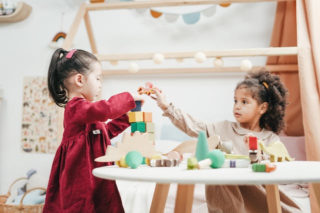 zwei Kinder spielen gemeinsam mit Bauklötzen